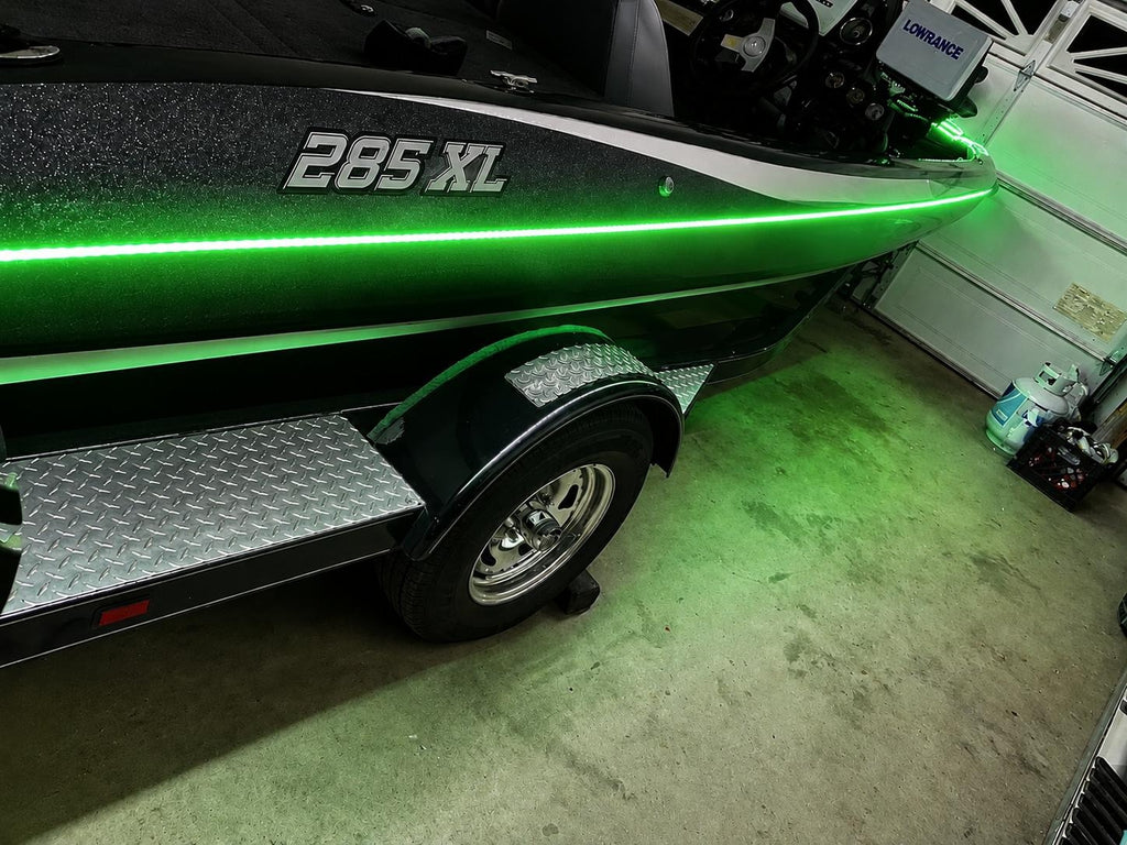 Green boat with '285 XL' marking on a trailer inside a garage.