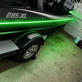 Green boat with '285 XL' on a trailer in a garage.